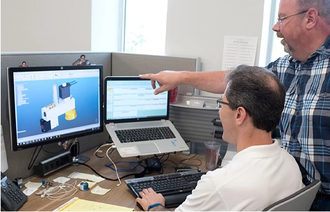 Photo of Engineers looking at schematics on a computer